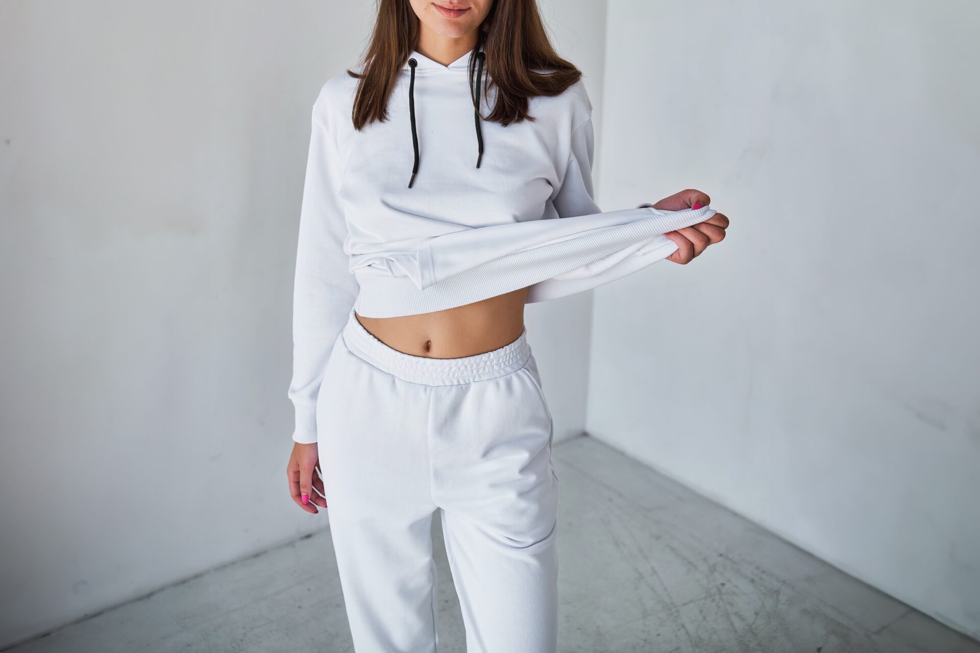 A young woman poses in a white hoodie for a mock-up template. A print and branding design concept. A girl in a casual shirt and pullover in a studio